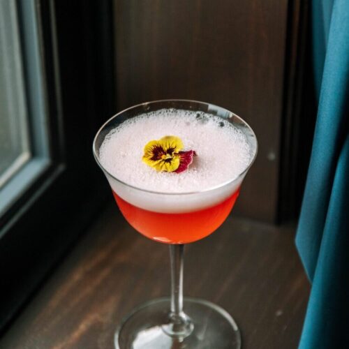 Red cocktail with foam and a flower garnish at our Kansas City hotel bar