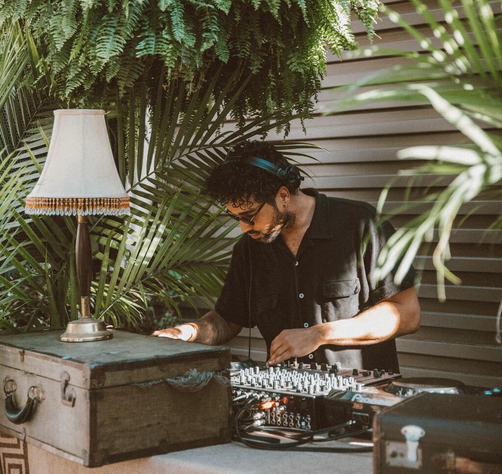 DJ surrounded by large plants at our rooftop bar in Kansas City, MO